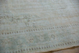 Distressed Oushak rug's pile showing mostly even wear, exposed foundation, and pale seafoam.