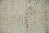 Distressed Oushak rug detail: low pile texture with mostly even wear, beige, ivory, pale seafoam.