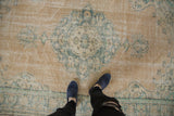 Distressed Oushak carpet detail: beige field, pale teal palmettes, and cross hatch weave.