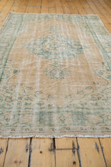Distressed vintage Oushak carpet, close-up of faded beige pile, cross-hatch foundation, and mint green patterns.