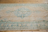 Textural close-up of distressed Oushak rug pile with beige field and faded seafoam green.