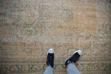 Worn texture and foundation visible on distressed Oushak rug with pale green vinery.