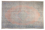 Distressed Vintage Oushak carpet with dusty blush field, faded floral medallion, mostly even wear.