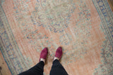Distressed Oushak rug with dusty blush field, faded blue and mint green floral patterns.