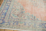 Distressed Oushak rug border detail, faded royal blue and mint green on dusty blush, with even wear.