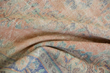 Textured, distressed Oushak rug pile showing even wear, dusty blush, and pale blue motifs.