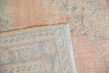 Distressed vintage Oushak carpet pile with dusty blush tones, visible woven back and fringed edge.