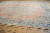 Distressed vintage Oushak rug border showing faded royal blue and blush floral patterns.