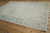 Vintage distressed Oushak carpet with faded ivory field, pale teal palmette border, and mostly even wear.