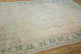 Texture of distressed vintage Oushak rug showing ivory field and subtle teal border.