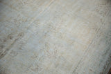 Distressed Oushak carpet with worn pile, revealing muted ivory, mint, and brown motifs.