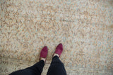 Distressed vintage Oushak carpet with faded apricot, ivory, and teal vinery and worn knot heads.