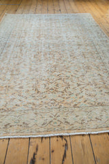 Faded distressed Oushak carpet with worn vinery pattern, apricot, ivory, charcoal hues, and fringe.