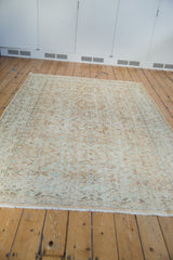 Distressed vintage Oushak carpet detail: faded apricot, ivory, teal vinery with foundation showing through.