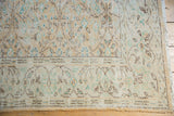 Distressed Oushak rug corner, faded apricot vinery, visible foundation, and intact selvage.