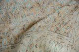 Distressed Oushak carpet texture showing knot heads, faded apricot, ivory, and teal vinery.