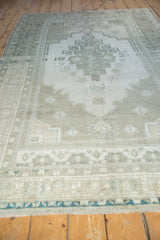 Stepped medallion and border detail on a distressed vintage Oushak rug, gray and seafoam.