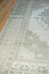 Distressed Oushak carpet's decorative border and corner spandrel in muted gray, ivory, seafoam green.