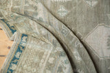 Distressed Oushak rug's hand knotted pile, muted seafoam green, gray, and blue border detail.