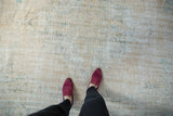 Worn pile of a distressed vintage Oushak carpet, with faded beige and sage green patterns.