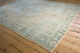Distressed vintage Oushak rug, worn to foundation, with faded beige, sage, and teal border.