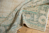 Textured pile of a distressed vintage Oushak carpet in faded beige and sage green.