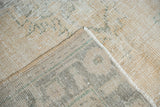 Textured distressed beige pile and woven foundation of a vintage Oushak rug corner.