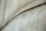 Distressed pile of vintage Oushak rug, showing faded seafoam green and copper patterns.