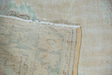 Vintage distressed Oushak rug showing worn faded pile, intact fringe, and woven foundation.