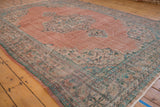 Distressed pale blush field with faded mint and aqua floral motifs on a vintage Oushak rug.
