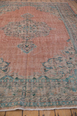 Pale blush field with muted aqua and mint patterns showing even wear on a vintage Oushak carpet.