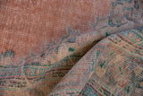 Folded section of distressed Oushak carpet, highlighting worn pile, blush, mint, and aqua blue tones.