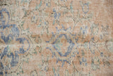Blush, sky blue, ivory, and green distressed Oushak rug pile with even wear to knot heads.