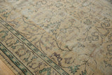 Distressed pile of a vintage Oushak rug showing worn ivory, green, and silver scrolling vinery.