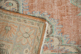 Distressed Oushak rug detail shows mostly even wear, visible foundation, pale terracotta, ivory, blue.