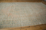 Distressed vintage Oushak carpet with faded floral motifs, exposed foundation, and soft apricot tones.