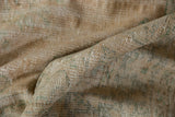 Textured close-up of distressed vintage Oushak carpet's worn pile, showcasing beige and muted mint tones.