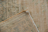 Distressed Oushak rug corner revealing wear to knot heads, a secured side cord selvage, and foundation.