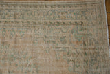 Distressed Oushak rug edge with visible foundation wear, faded mint patterns, and fringe.