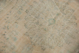 Distressed Oushak pile texture with faded floral motifs in mint green and apricot.