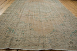 Textured distressed Oushak rug pile in muted beige with faded teal and apricot tones.