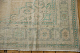 Distressed vintage Oushak rug corner, showing mostly even wear on ivory and seafoam green pile.
