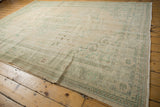 Distressed Oushak carpet corner, muted ivory and sea foam green patterns, mostly even wear to knot heads.