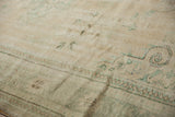 Distressed vintage Oushak rug texture showing mostly even wear and subtle green motifs.