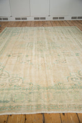 Distressed Oushak pile texture featuring soft ivory and faded mint green patterns.