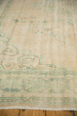 Distressed vintage Oushak rug with mostly even wear, ivory pile, and subtle green pattern.