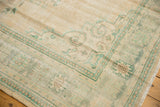 Corner of distressed Oushak rug with sea foam green geometric border, faded pile.