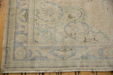 Distressed vintage Turkish Oushak carpet corner, showing worn pile, faded blue motifs, and fringe.