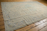 Corner detail of distressed Oushak rug, low pile, faded blue border, intact selvage.