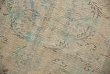 Distressed vintage Oushak carpet showing faded floral patterns with pile wear to foundation.